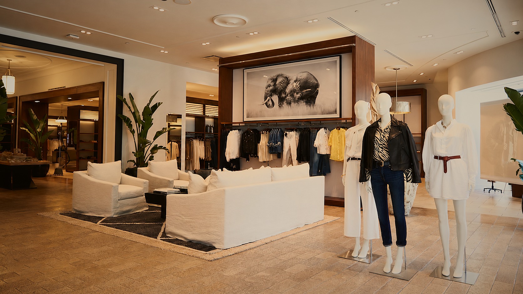 Banana Republic flagship interior with white linen sofas, styled mannequins, and a large elephant photograph above the clothing racks