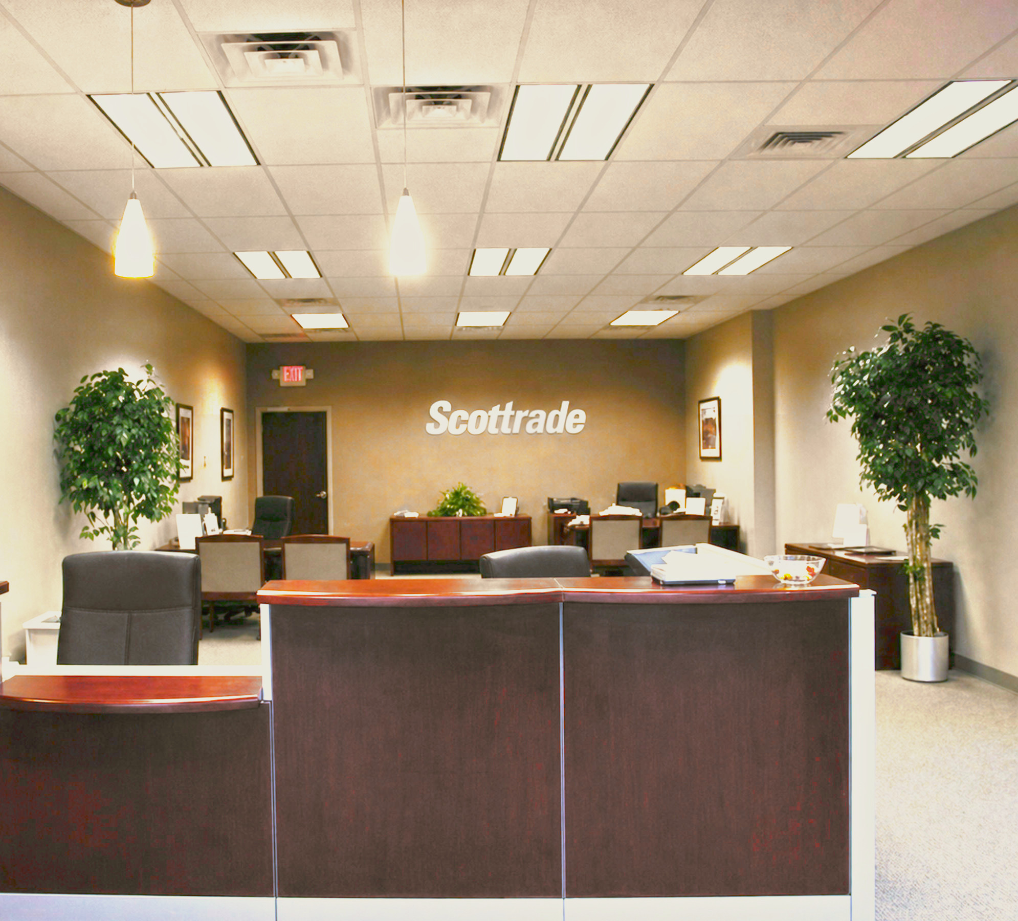 Scottrade branch office reception with cherry desk, brushed-metal logo wall and pendant lights